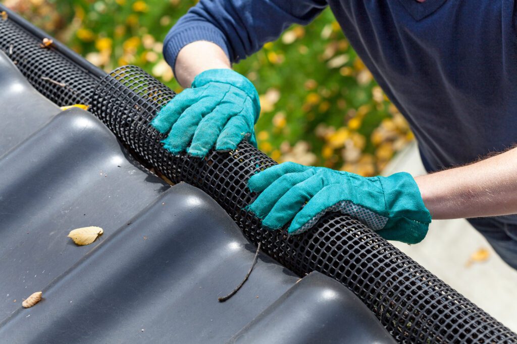 Man installing leaf mesh in roof gutters